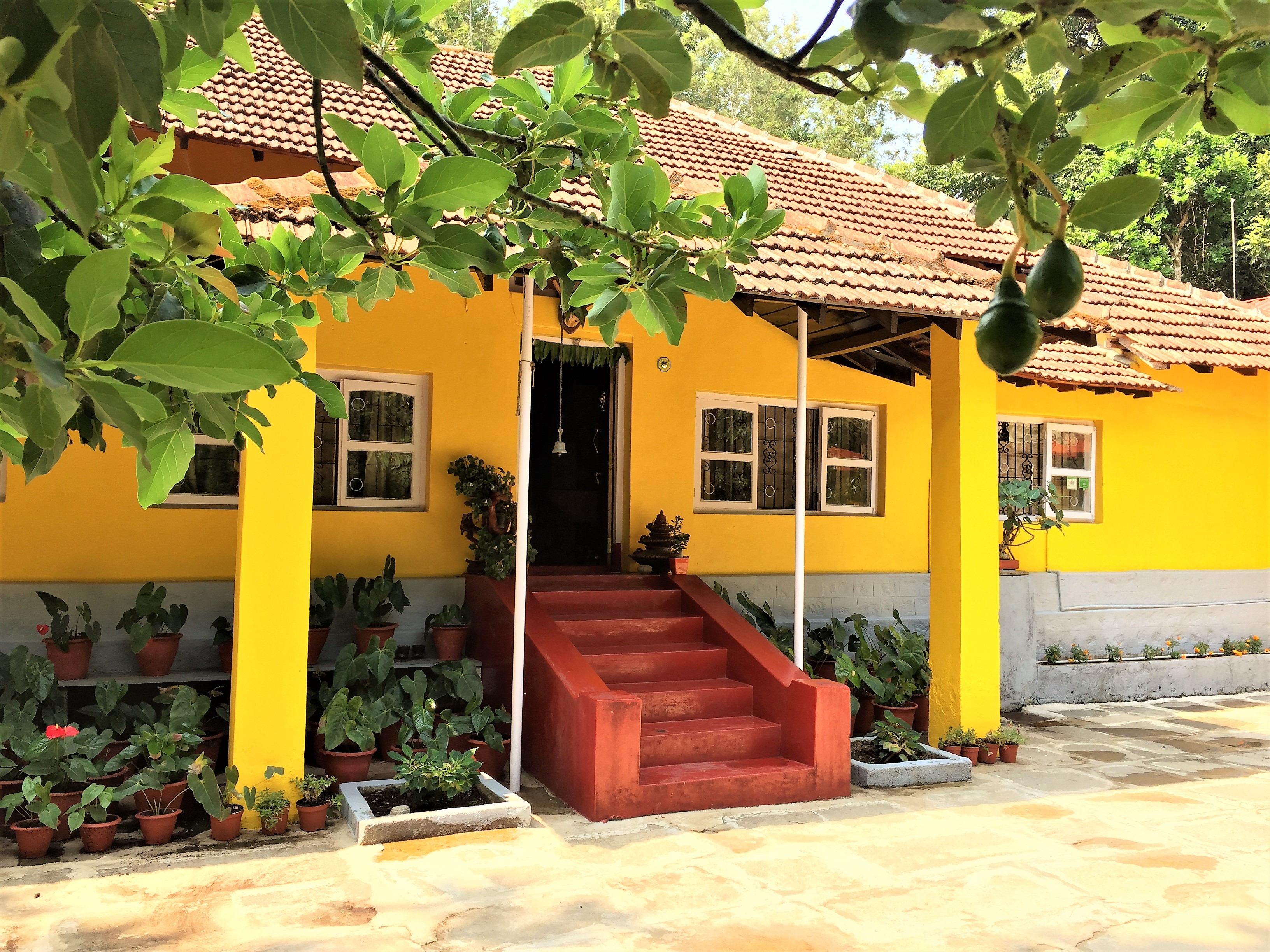 Best heritage homestay in Chikmagalur — Guddadamane yellow ancestral house with red terracotta staircase